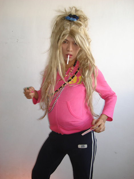 British chav girl chavette smoker posing with blonde wig and cigarette and bling with pink and blue tracksuit