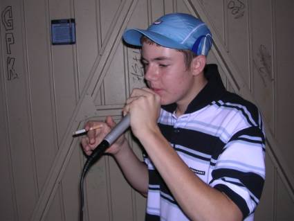 British chav pikey smoker with baseball cap singing karaoke microphone